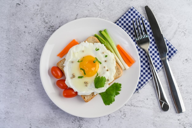 Free photo a fried egg laying on a toast, topped with pepper seeds with carrots and spring onions.