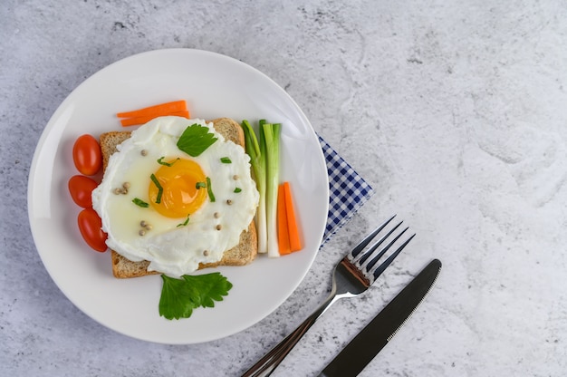 Free photo a fried egg laying on a toast, topped with pepper seeds with carrots and spring onions.