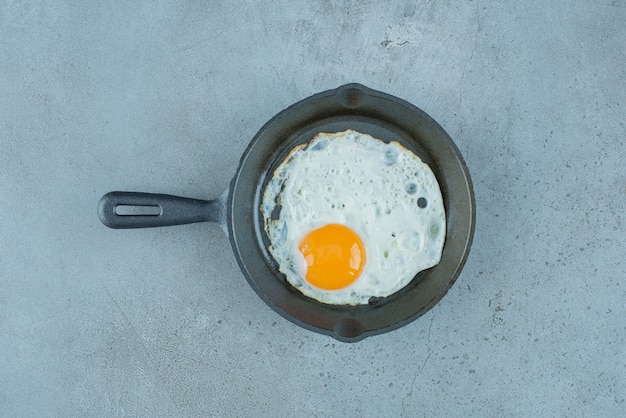 Fried egg in a pan on marble background. High quality photo