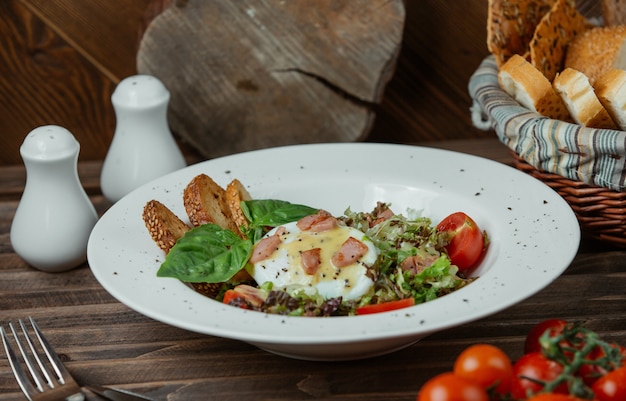 Fried egg in a plate with toastes and green salad 