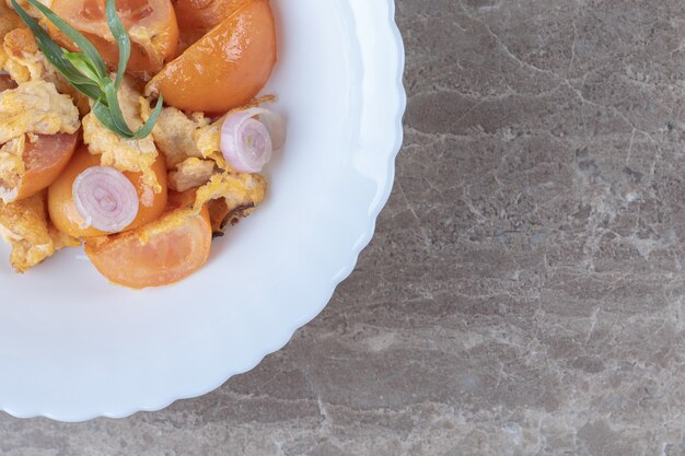 Fried egg and tomatoes on white plate.