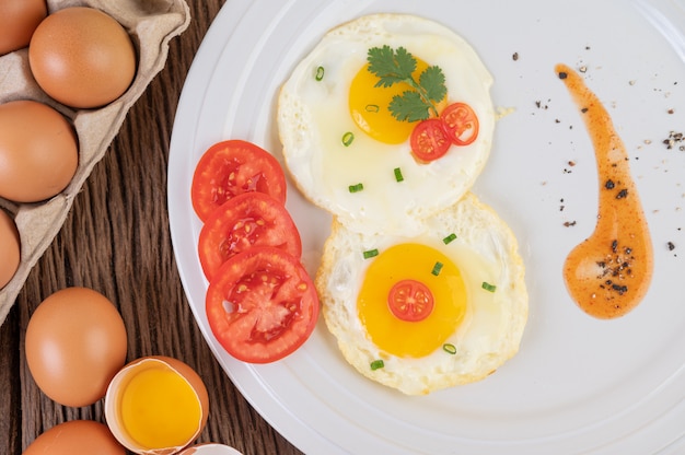 Free photo fried egg on a white plate with sliced ​​spring onion and sliced ​​tomatoes