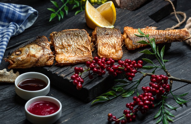 Free photo fried fish with cranberries on wooden board