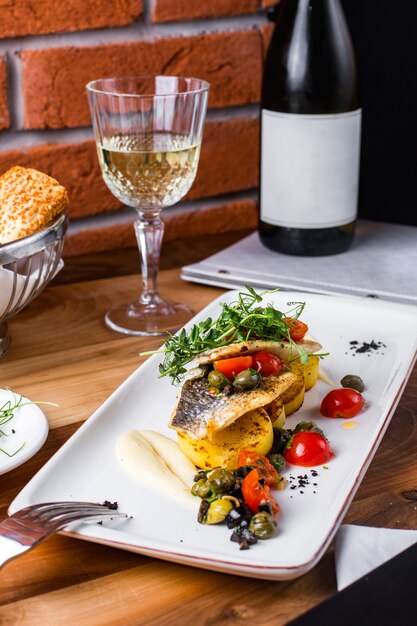 Fried fish with potatoes, tomatoes, sauce and greens