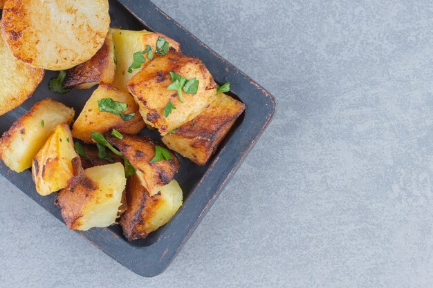 Fried fresh potatoes in black plate on grey background. 