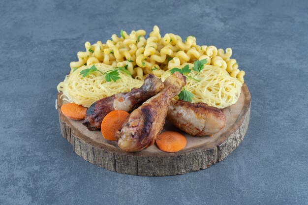 Fried legs, macaroni and spaghetti on wood piece. 