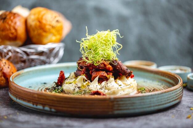 Fried meat placed on mashed potato garnished with shredded bell pepper and thyme