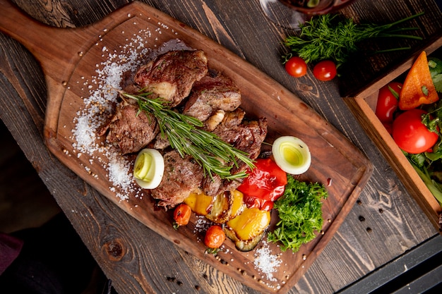 Free photo fried meat served with grilled vegetables onion and  rosemary sprig