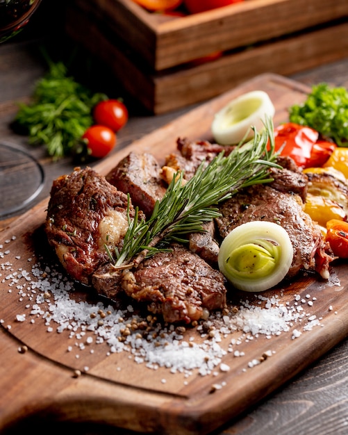 Fried meat served with grilled vegetables onion and  rosemary sprig