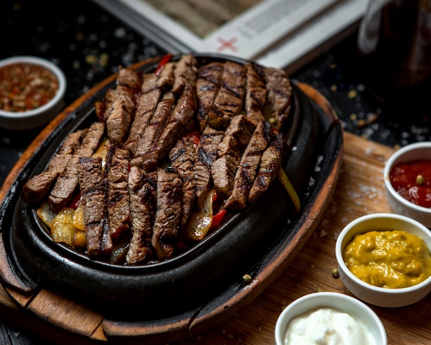 Fried meat slices with fried onion on the wooden board