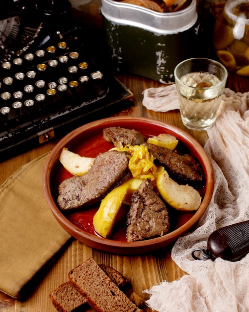 Free photo fried meat with quince in a clay pot