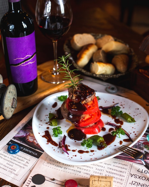 Free Photo fried meat with tomato slices, greens, sauce, rosemary sprig served with wine