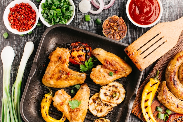 Free photo fried meat with vegetable and spiral sausage on wooden desk