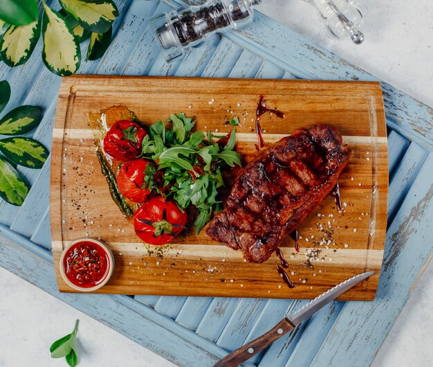 fried meat with vegetables on wooden board top view