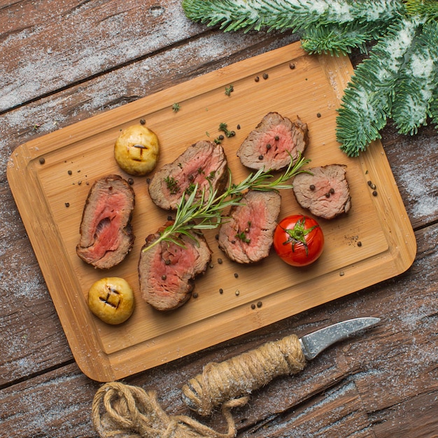 Fried meat with vegetables on wooden board