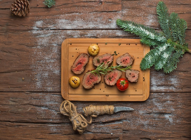 Fried meat with vegetables on wooden board