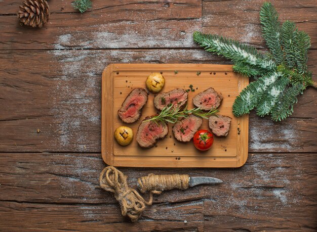 Fried meat with vegetables on wooden board