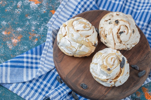 Fried meringue cookie with black raisines on a wooden board.