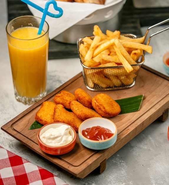 fried nuggets and french fries on wooden board