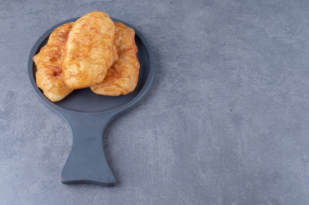 Fried in oil dough in a pan on marble table.