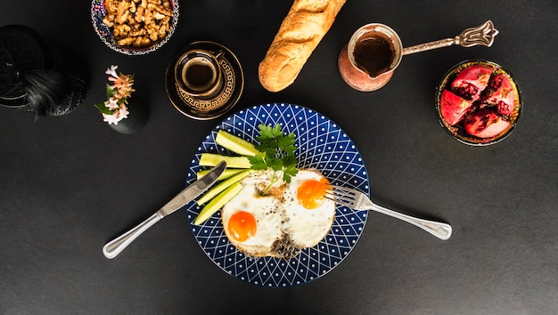 Free photo fried omelette with tea, bread and walnut bowl on black background