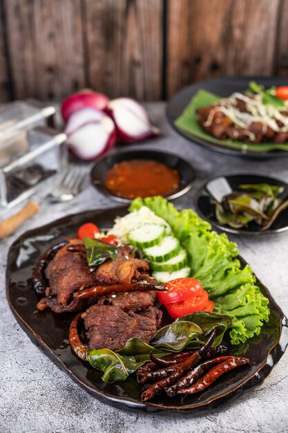 Fried pork topped with sesame placed in a black dish.