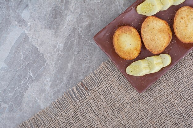 Fried potato slices and pickled cucumbers on plate.