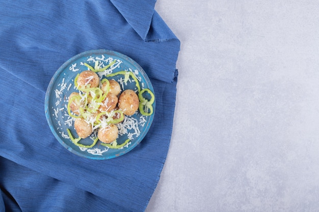 Fried potatoes decorated with cheese and pepper on blue plate. 