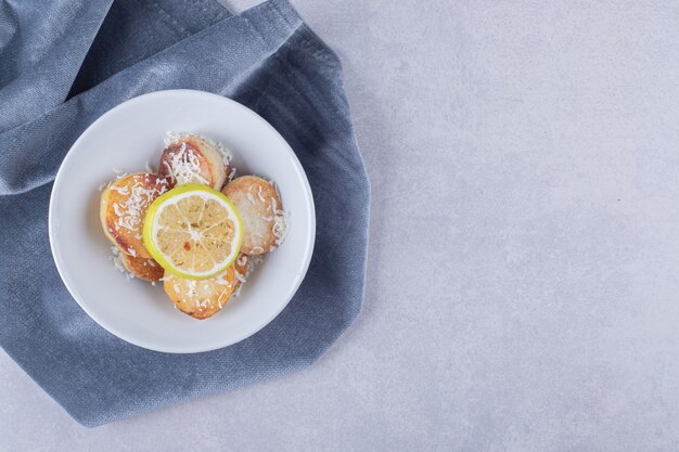 Fried potatoes garnished with grated cheese and lemon on white plate. 