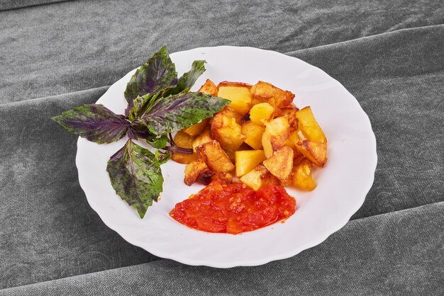 Fried potatoes with herbs in a white plate.