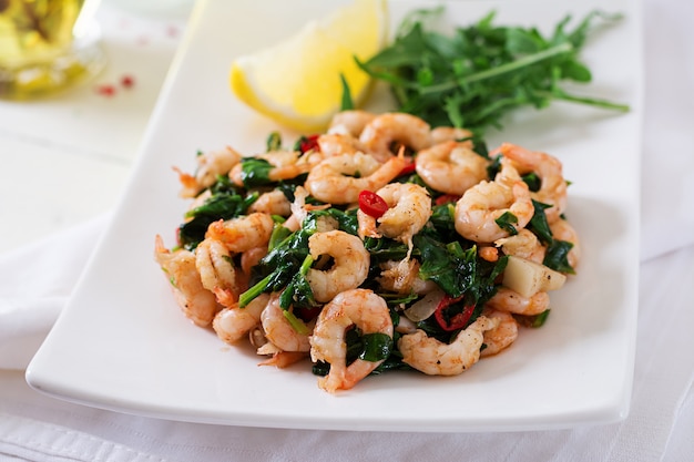 Fried prawns or shrimps with spinach, chili and garlic in white plate.