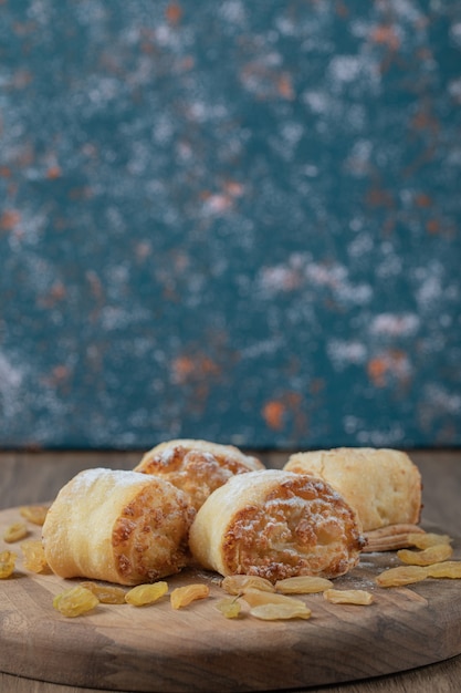 Free photo fried roll cookies with white raisins and sweet stuffings on a wooden board.