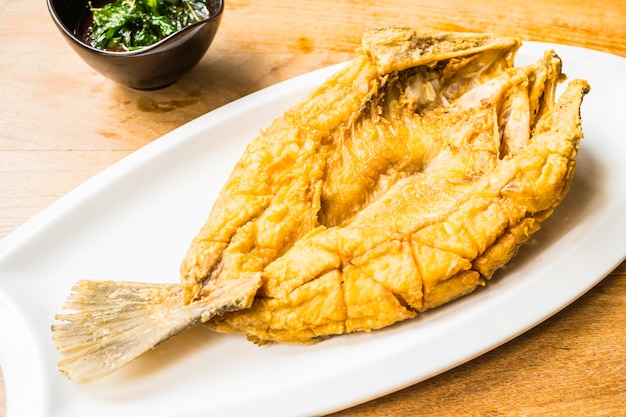 Fried sea bass fish in white plate with spicy and sweet sauce