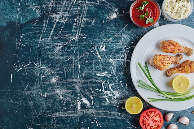 Free photo fried spicy chicken leg in a white plate with lemon.