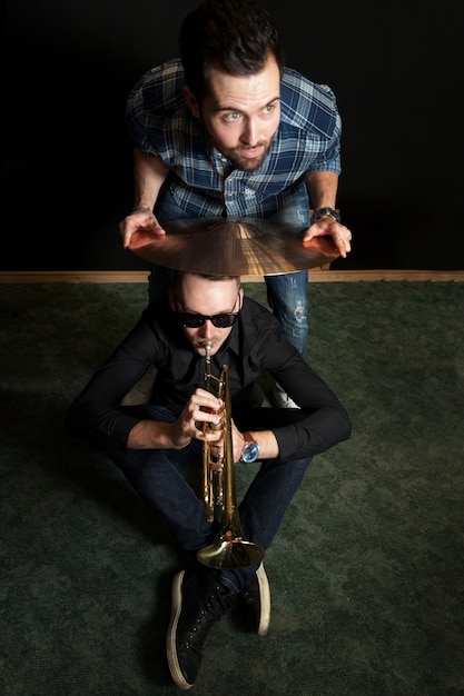 Free photo friend holding cymbal above trumpet