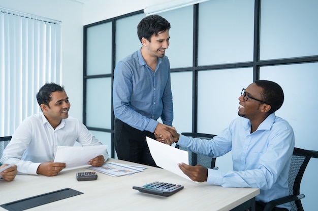 Friendly Caucasian and Afro American business people shaking hands.