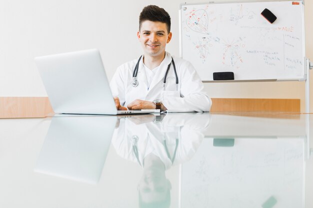 Friendly doctor working with laptop