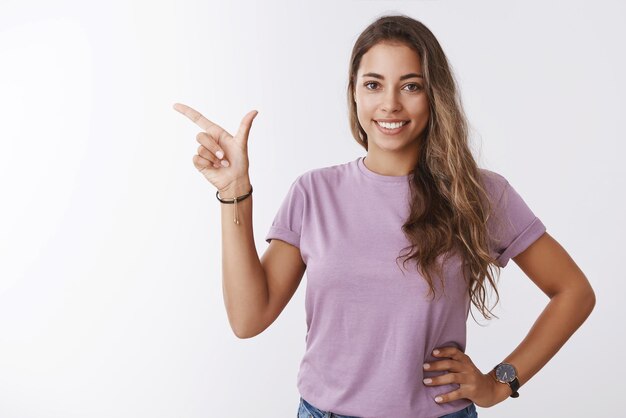 Friendly smiling  girl pointing finger to the side