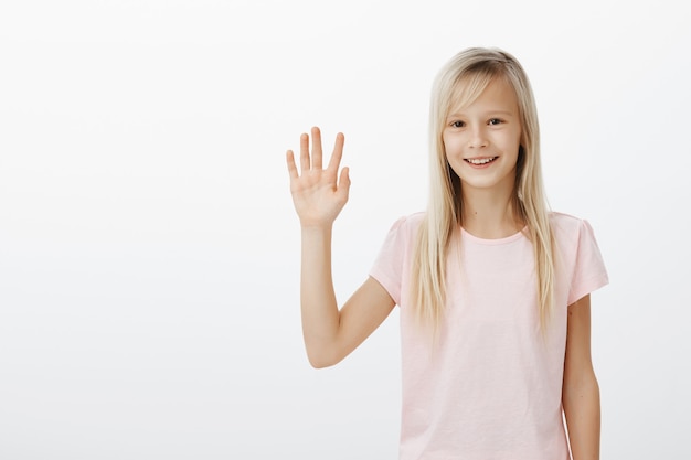 Friendly smiling kid saying hello, little woman waving hand say hi