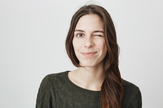 Friendly smiling woman give encouraging wink