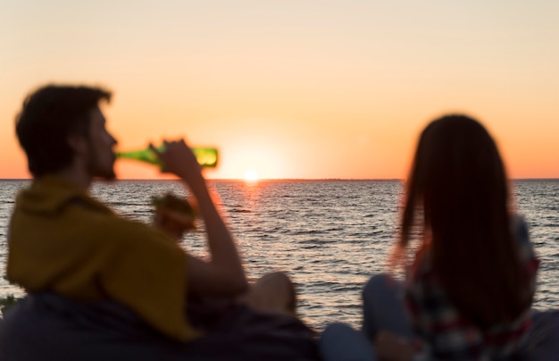 Free photo friends admiring the sunset while having a beer