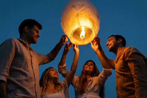 Friends at the beach launching lantern during the night