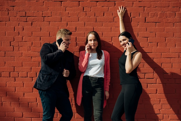 Friends calling on phones leaning on wall