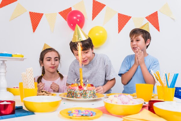 Friends clapping while boy cutting his birthday cake at home