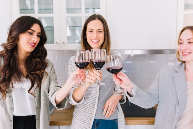 Free photo friends clinking glasses on kitchen