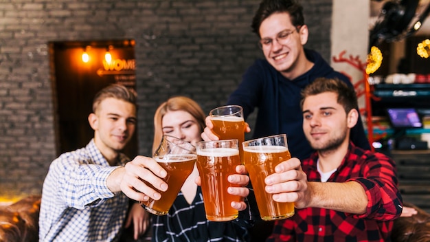 Friends clinking glasses with beer in pub