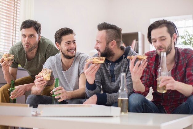 Friends drinking beer and eating pizza