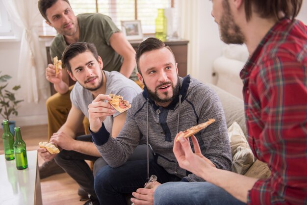 Friends drinking beer and eating pizza