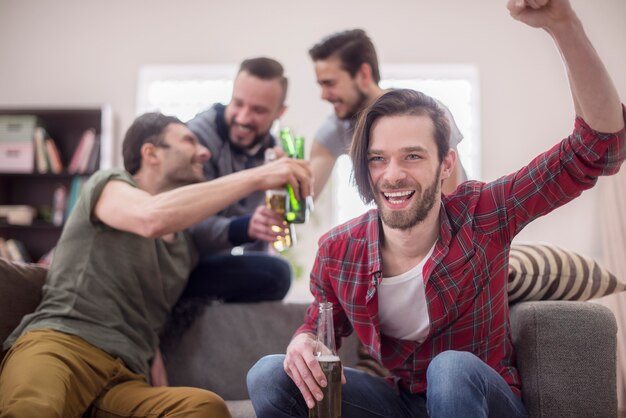 Friends drinking beer and watching football match