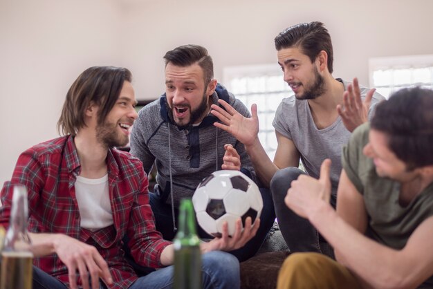 Friends drinking beer and watching football match